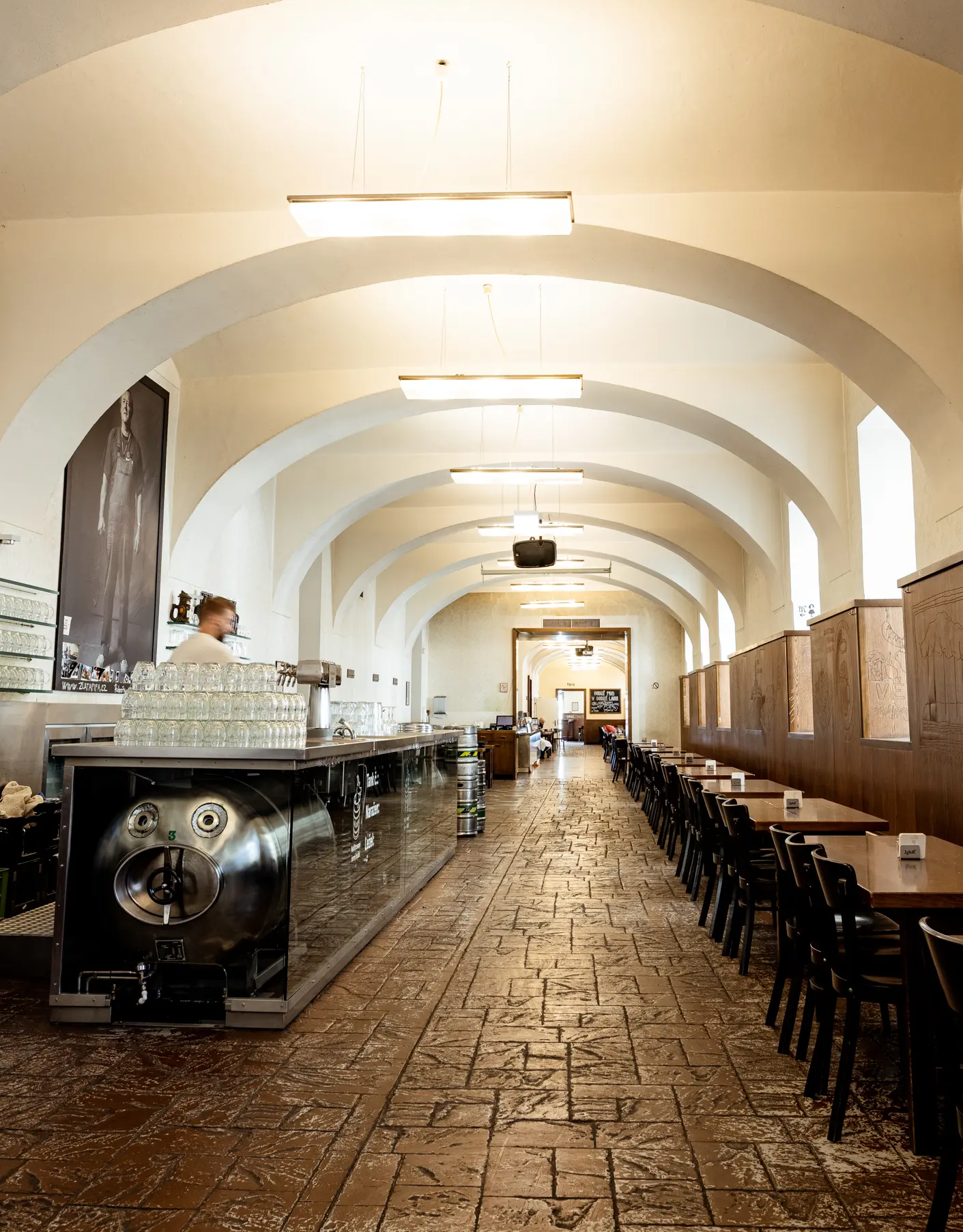 Interiér restaurace Lokál Dlouhá s klenutým stropem, dlouhou výčepní linkou a řadami stolů v historickém prostoru.