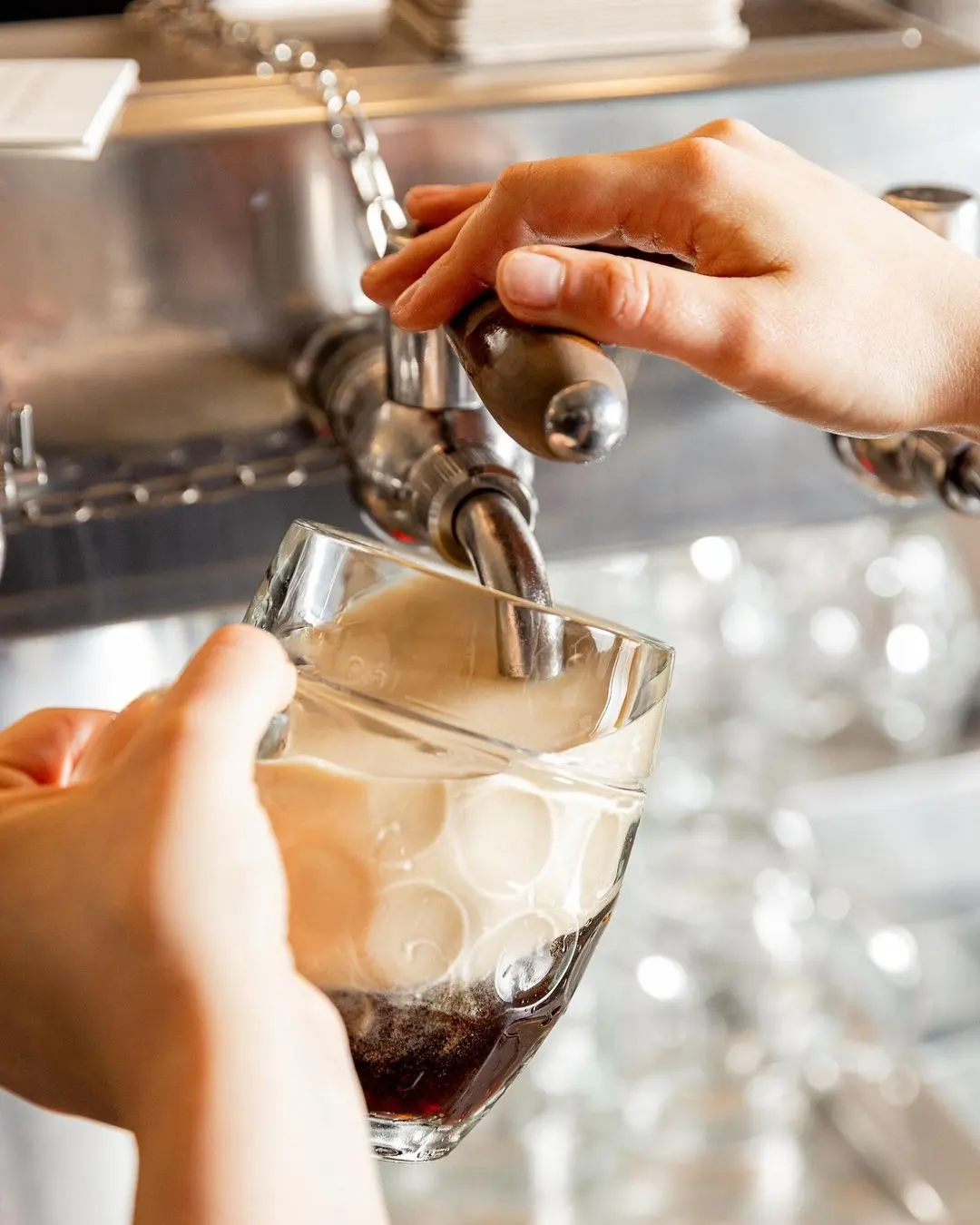 Pouring dark beer from a tap into a glass, close-up of hands and beer foam in a Czech pub.