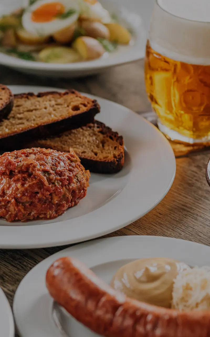 Beef tartare with bread and a pint of beer on a wooden table.