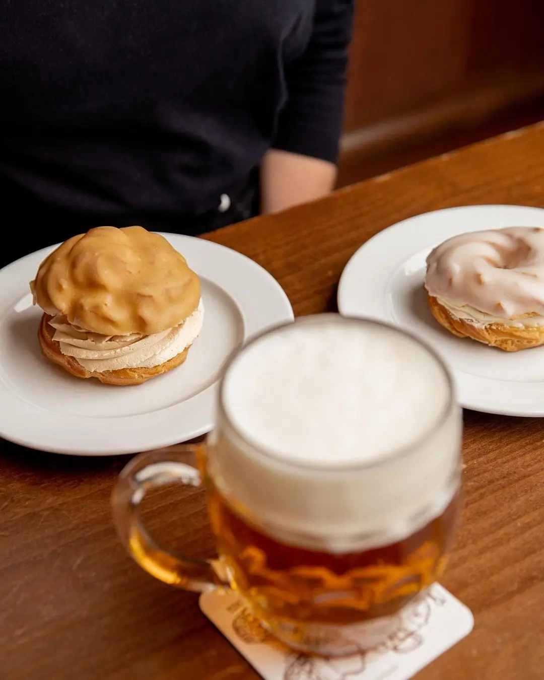Traditional Czech pastries profiterole and ring cake served on plates with a freshly poured beer on the table.
