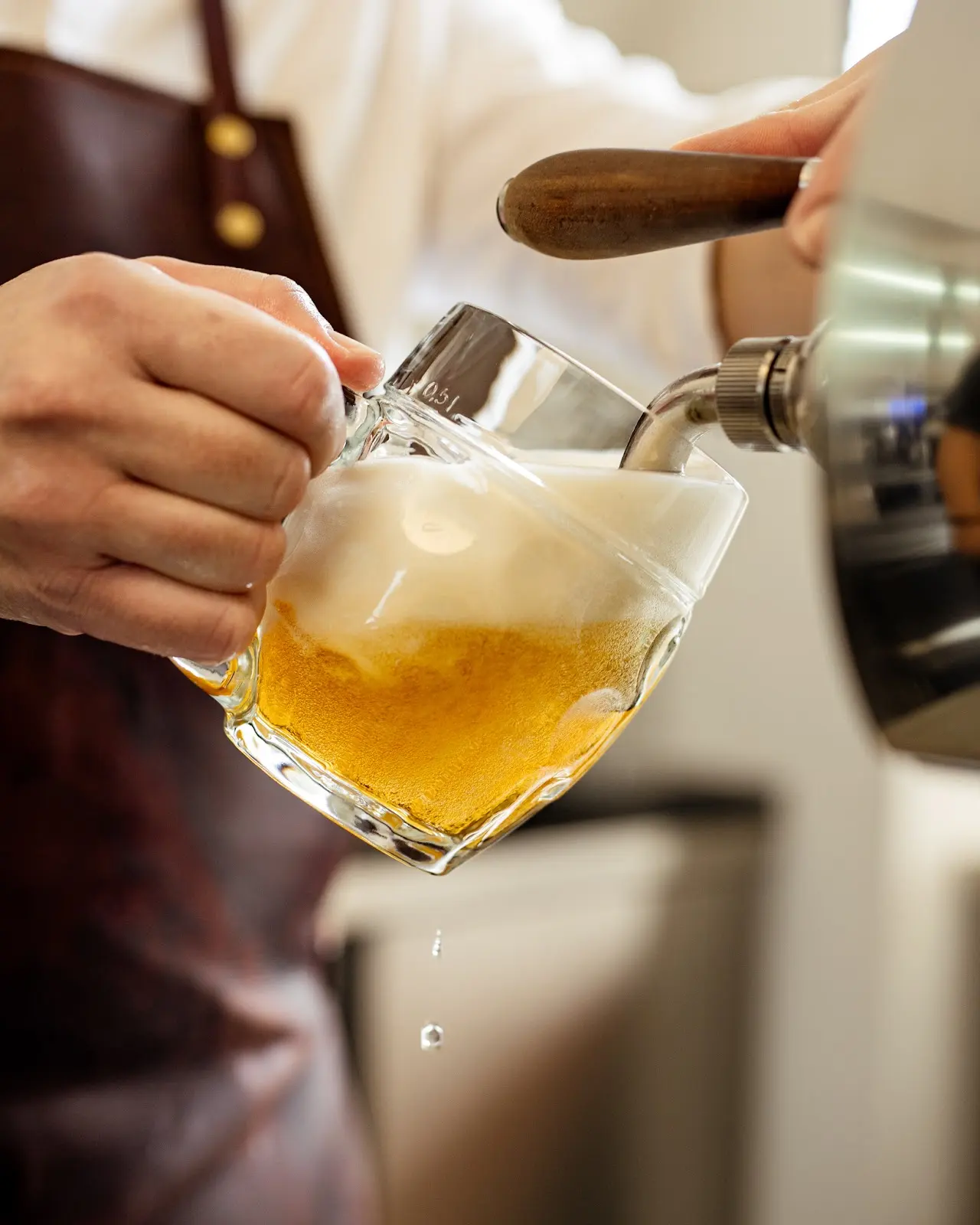 Čepování čerstvého piva do půllitru v restauraci Lokál, detail pěny a zlatavého ležáku.