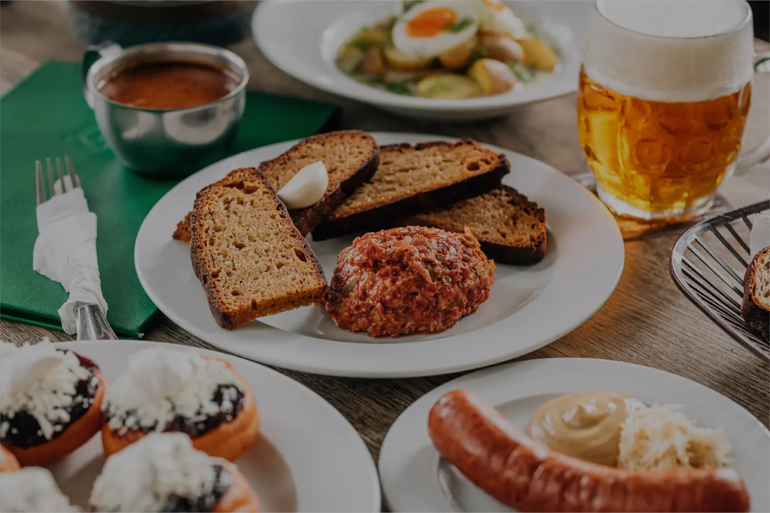 Beef tartare with toasted bread, garlic, and a pint of beer on the table.