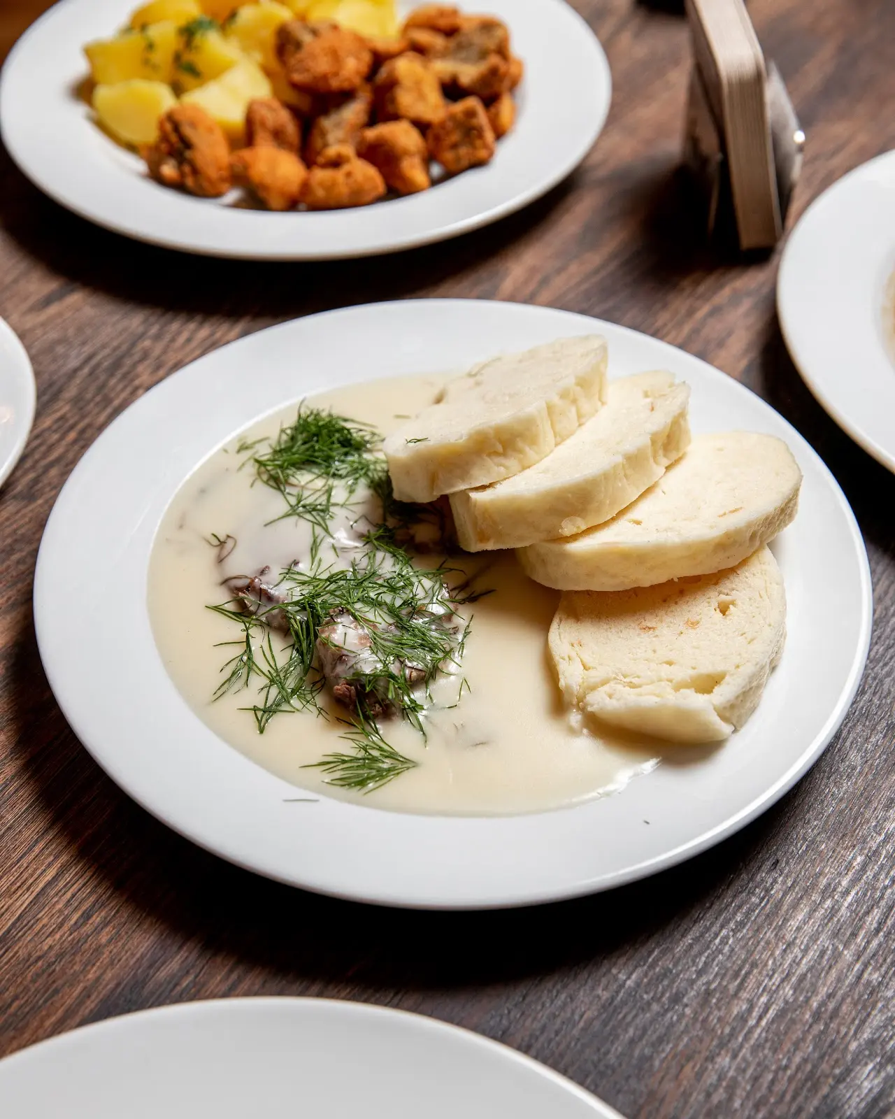 Hovězí maso v krémové koprové omáčce s houskovým knedlíkem, tradiční česká kuchyně servírovaná v restauraci.